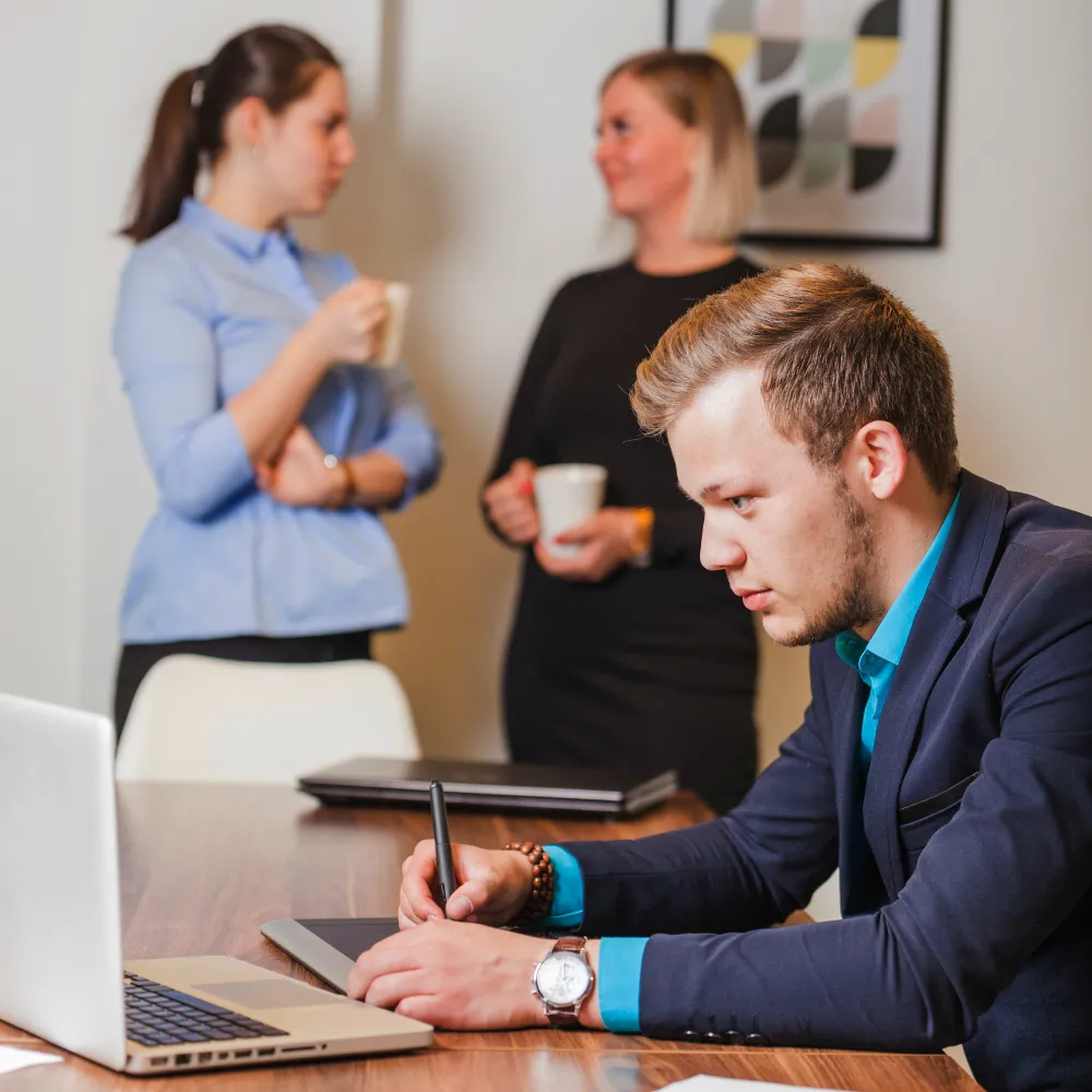 Healthcare professional completing prior authorization documentation on a digital tablet while colleagues discuss case details, representing ePA prior authorization workflow and insurance approval management.