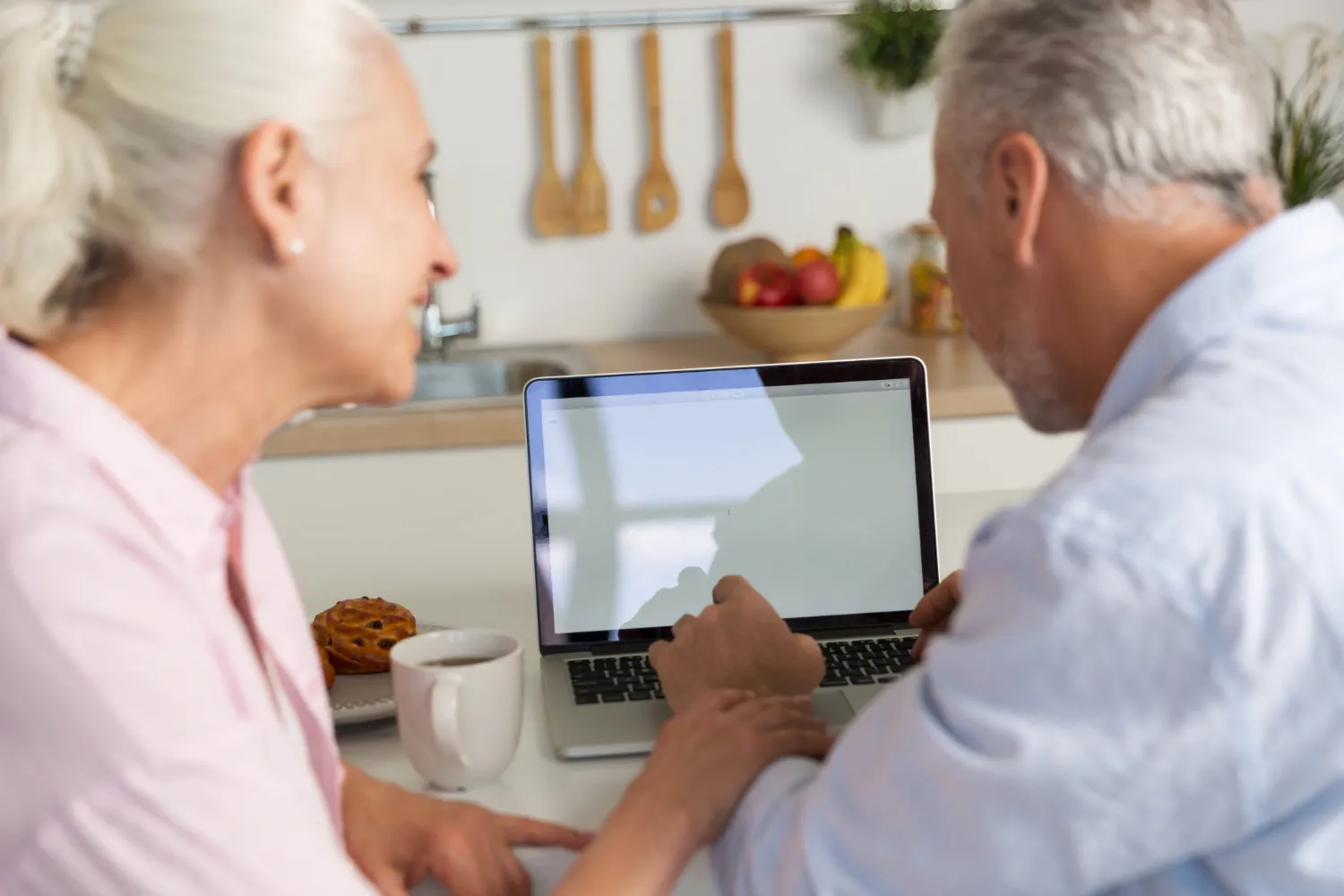 Older adults reviewing healthcare information on a laptop at home, illustrating prior authorization services that simplify insurance approvals and improve access to timely care.