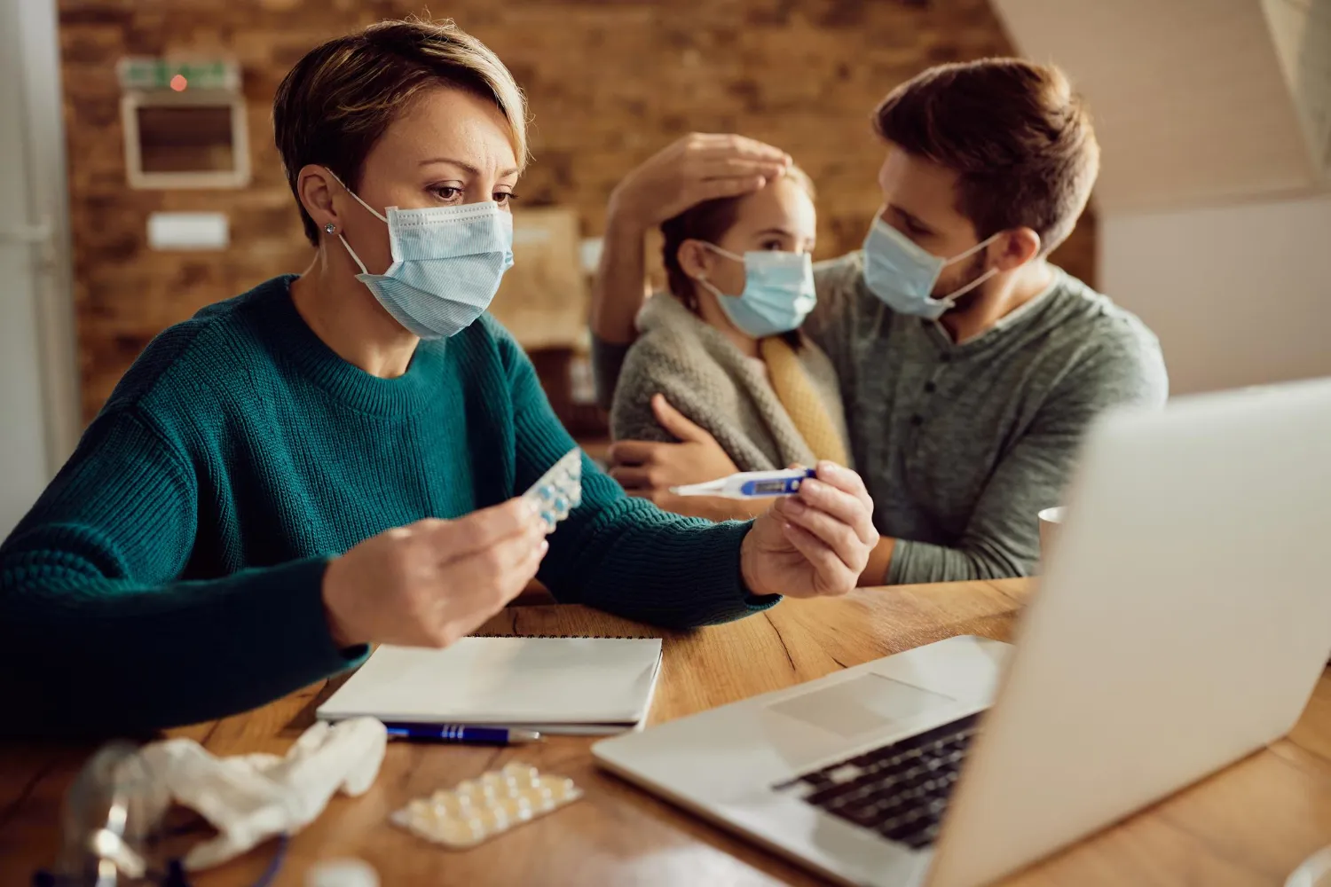 Parent checking child’s temperature while reviewing medication information online for medication authorization and prescription approval support