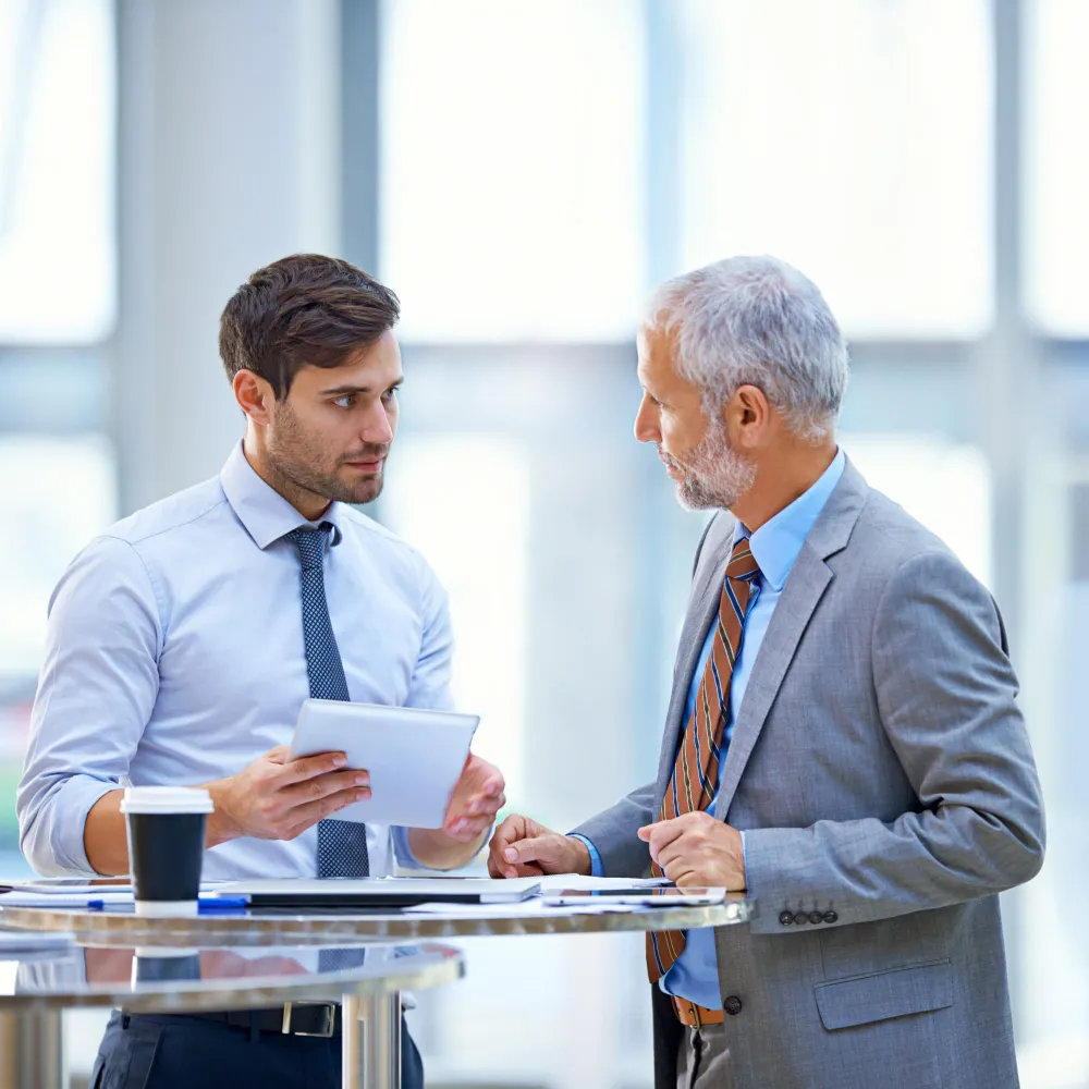 Business professionals discussing healthcare coverage and utilization review using digital documents, supporting Prior Authorization for Payors with efficient, customized authorization solutions.