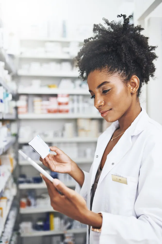 Pharmacist reviewing medication information on a tablet as part of the pharmacy prior authorization process.