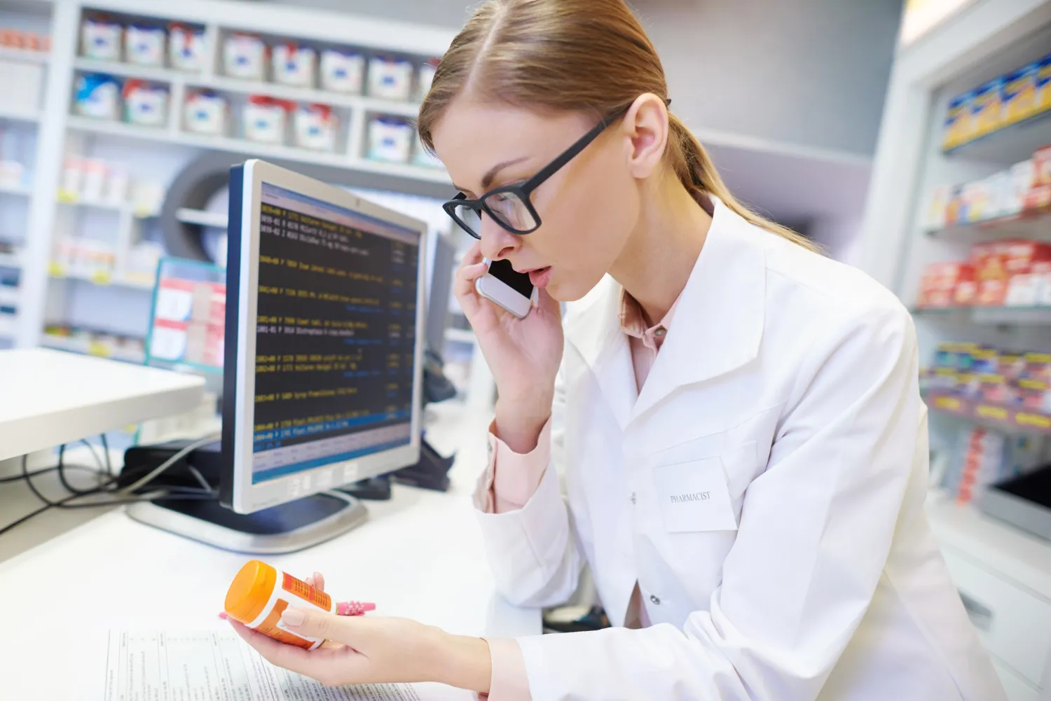 Pharmacist reviewing medication information while handling electronic prior authorization integration.